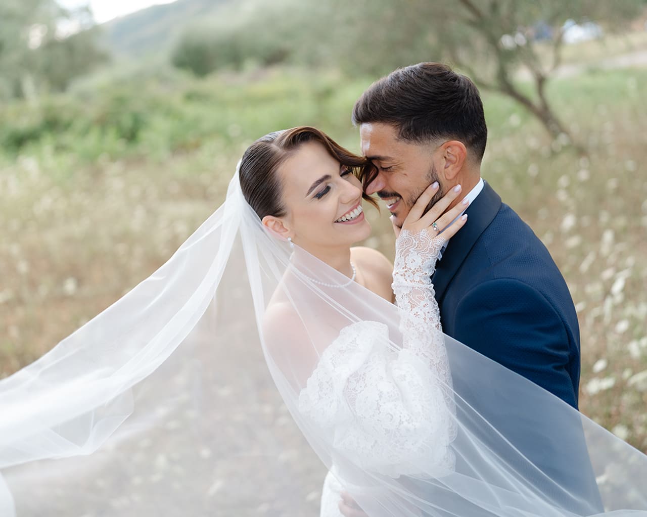 Sposi che sorridono e si divertono tra gli ulivi durante un servizio fotografico di matrimonio